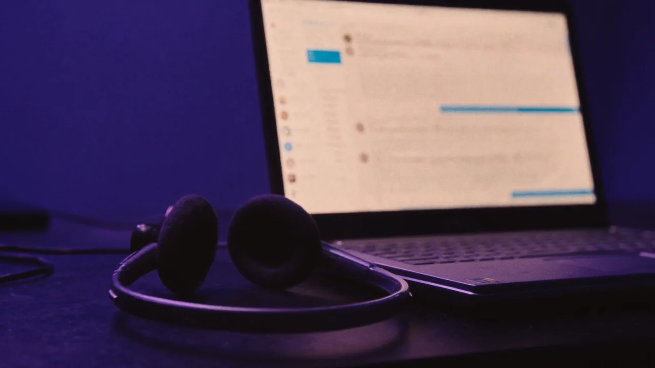 Un casque d’écoute abandonné à côté d’un ordinateur portable resté allumé