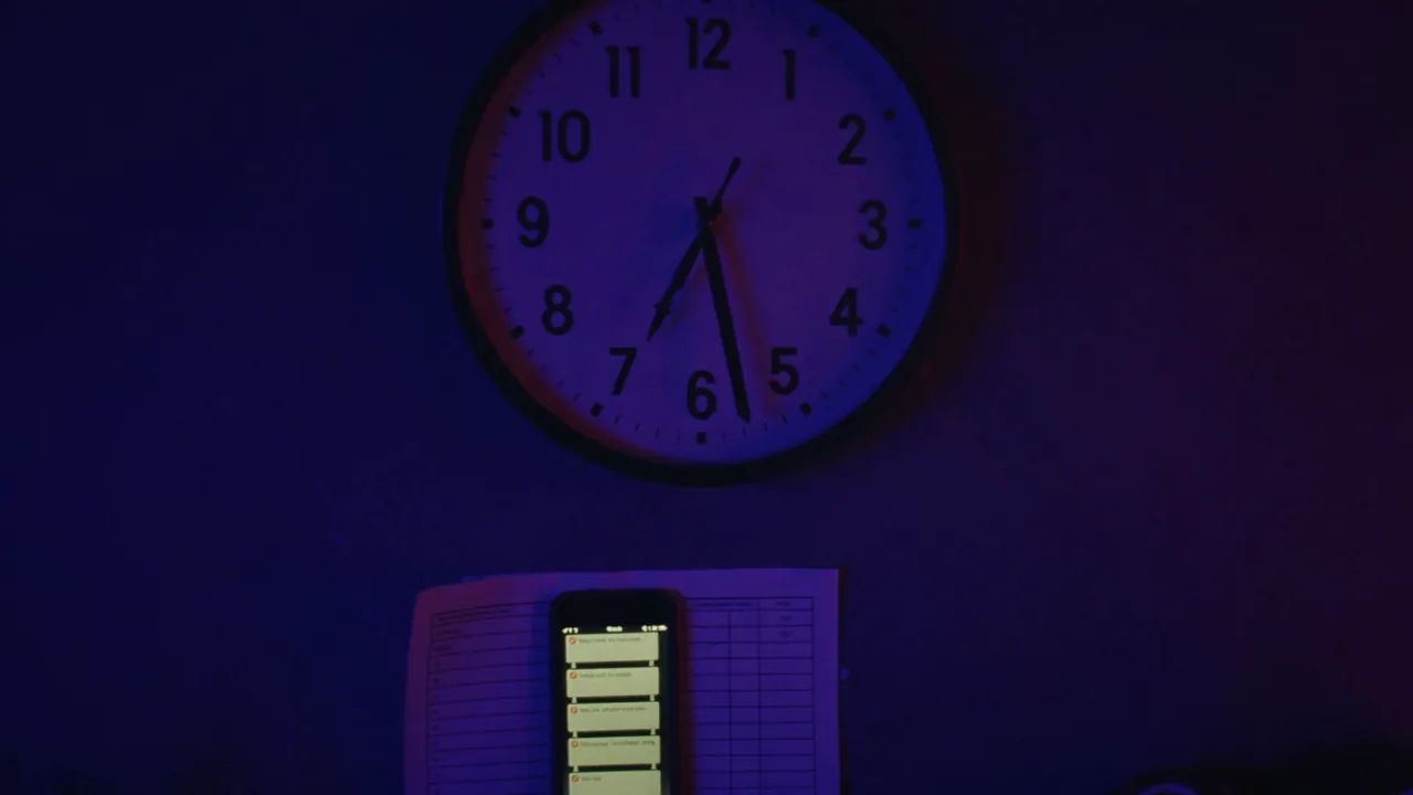 Une horloge murale marquant 3 h 40, un téléphone en notifications et une feuille de planning
