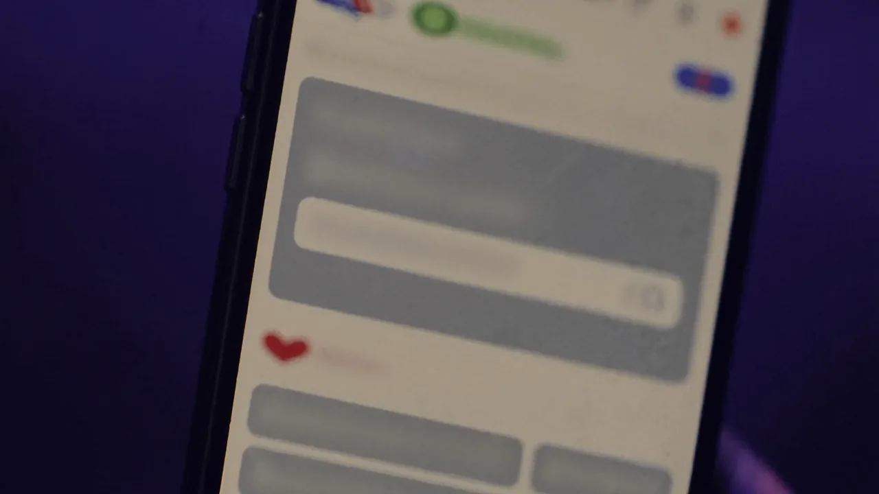 Un téléphone allumé dans le noir affichant une conversation, bulles de messages grises